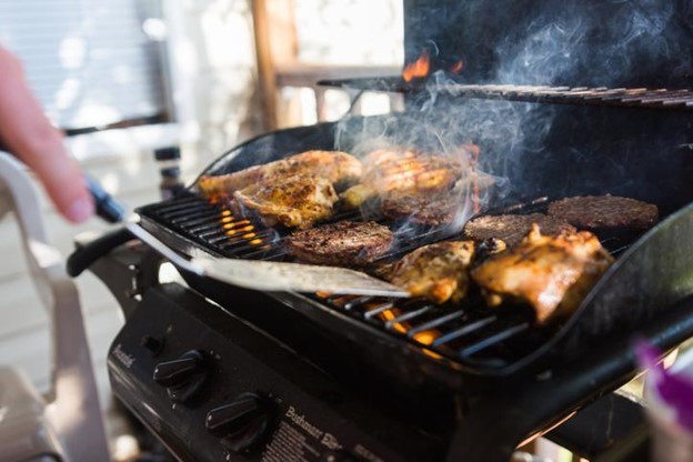 Chicken and burgers flame cooked on outdoor gas grill